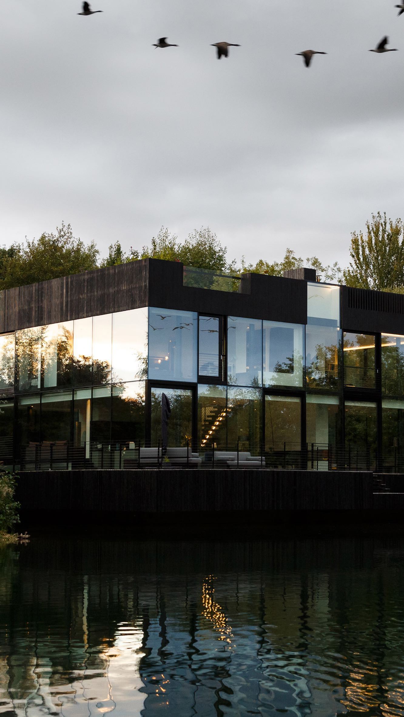 Egy erdőben elrejtett úszó üveg tóparti ház